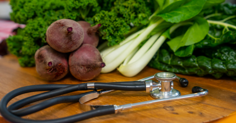 Stethoscope with beetroot and leafy green vegetables in the background