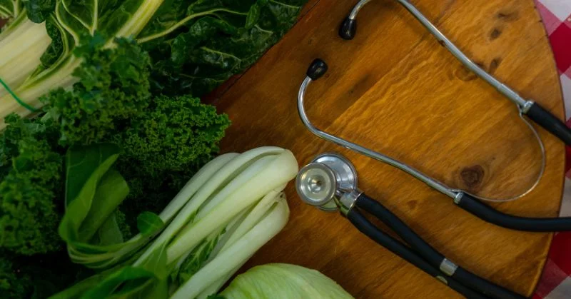 Stethoscope on a table with green vegetables