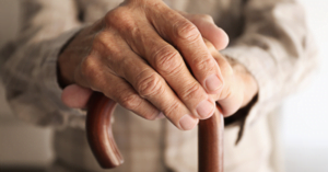 elderly persons hands on top of walking cane