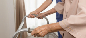 Older person using walking frame with assistance