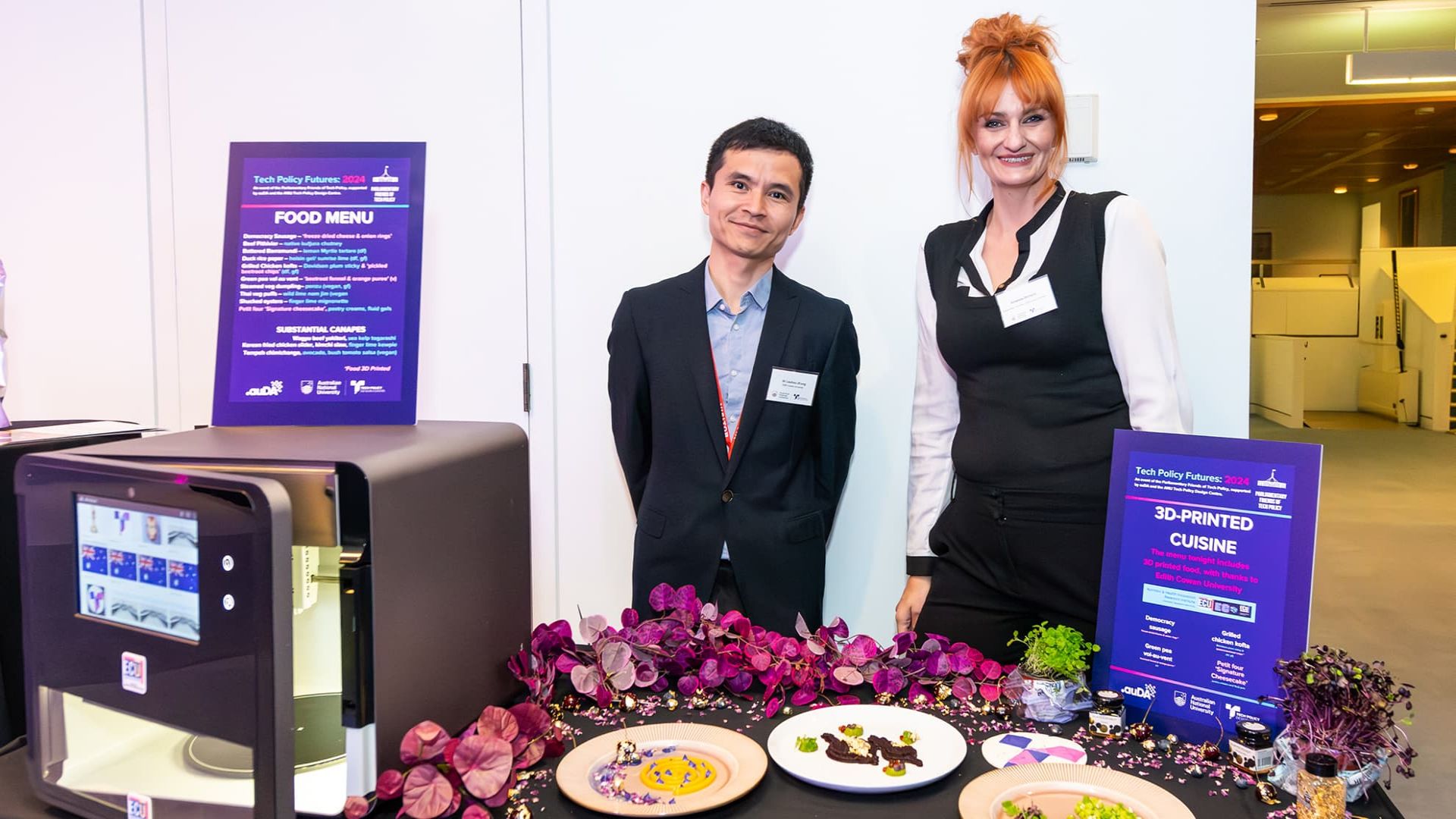 Dr Liezhou Zhong and Chef Amanda Orchard stand beside a table displaying dishes and a 3D food printer at the tech Policy Futures event.