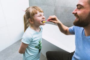 man brushing child's teeth